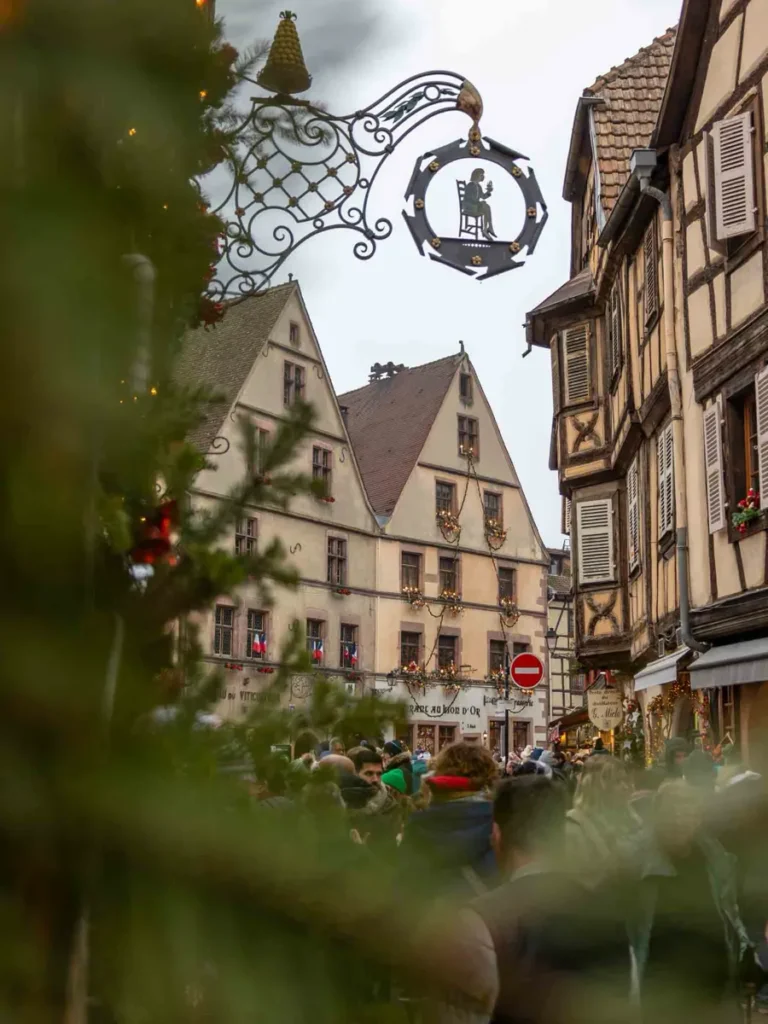Traditional houses and signs on a road with pedestrians during Christmas time in Kayserberg-Vignoble, France