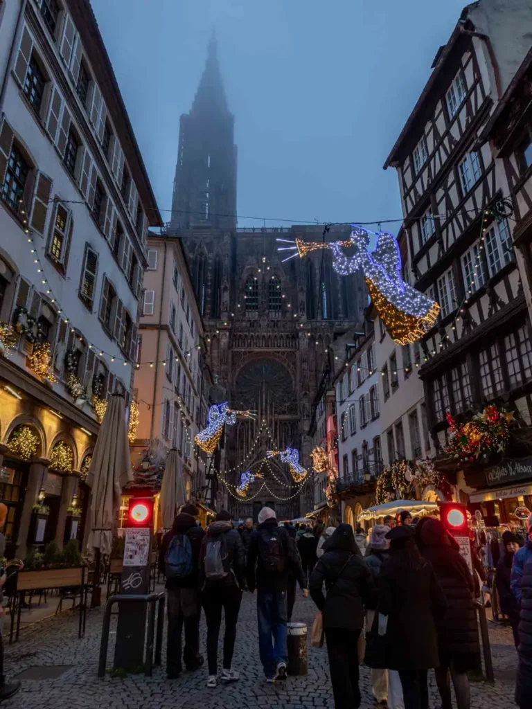 Cobble stone road with pedestrians surrounded by half timbered houses, leading to a Cathedral in Strasbourg, France