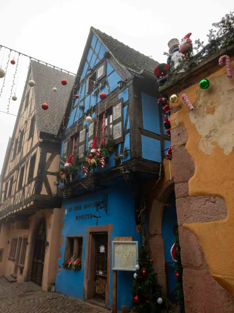 Colourful half-timbered houses in Riquewihr with Christmas decorations on a foggy day
