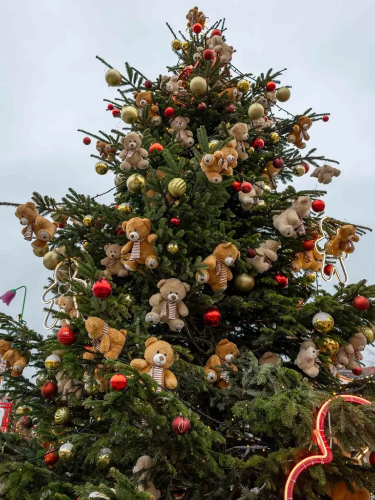 Christmas tree with different ornaments and teddy bears hanging on it