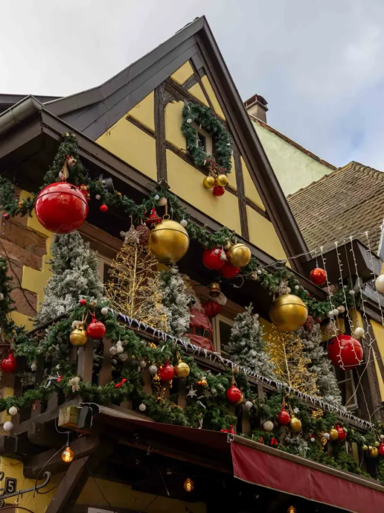 Yellow half-timbered house with festive Christmas decorations including golden and red Christmas ornaments
