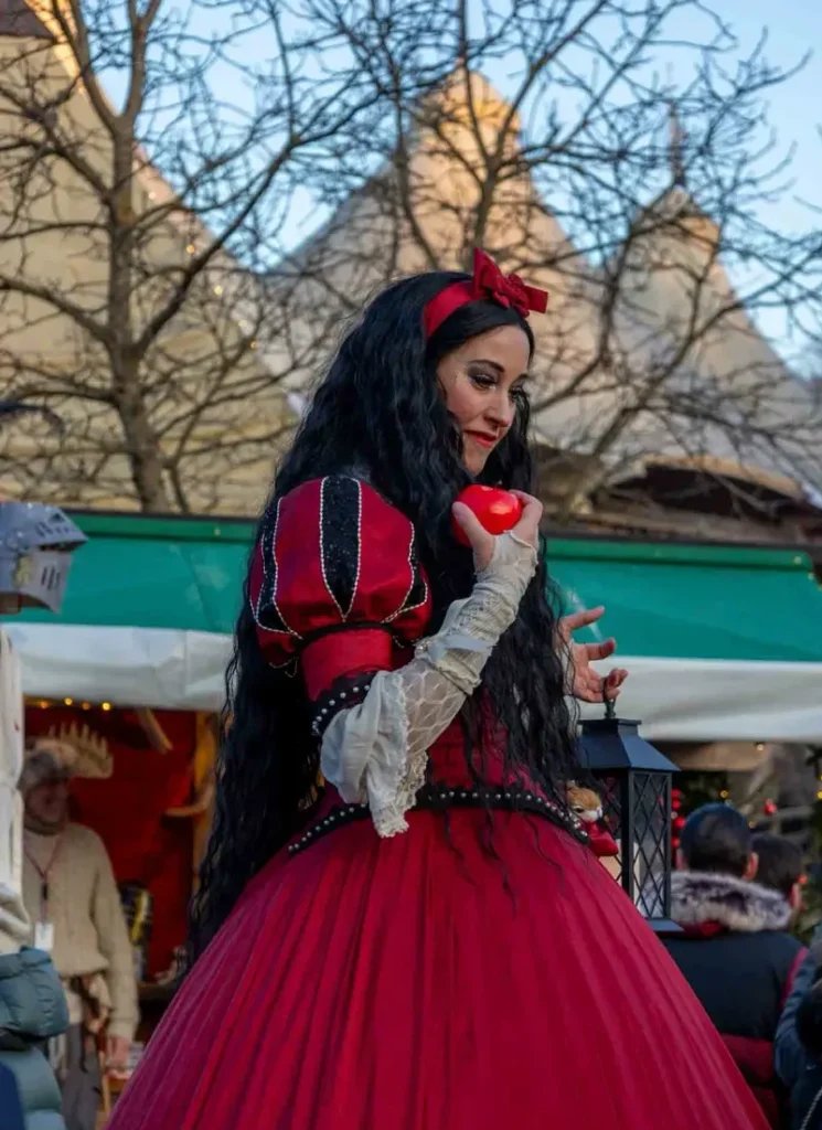 A woman dressed up as Snow White with a red dress and long black hair, holding an apple