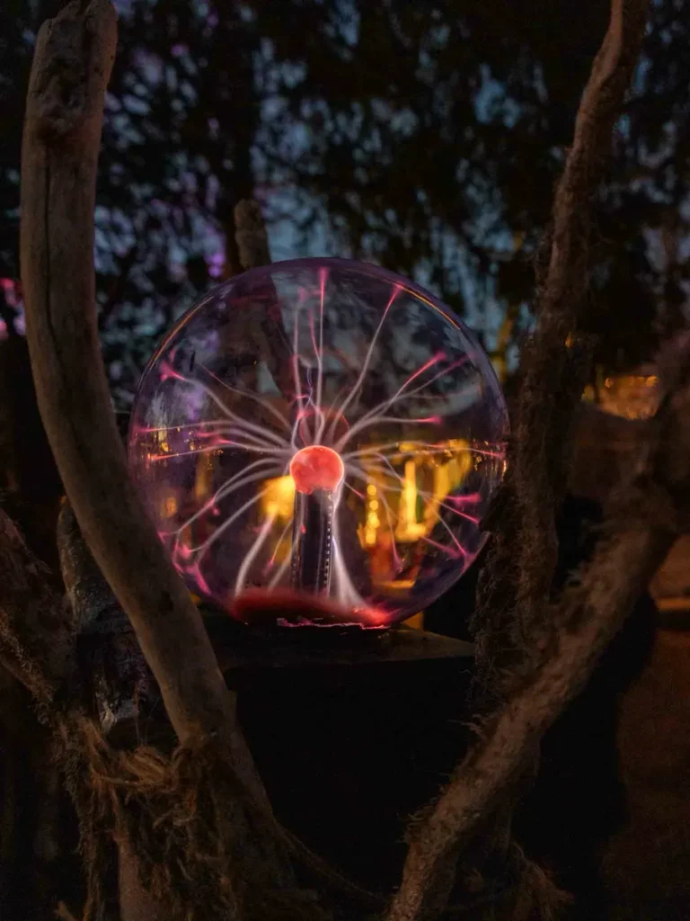 A crystal ball of a fortune teller with lights inside held by a tree at a Christmas market